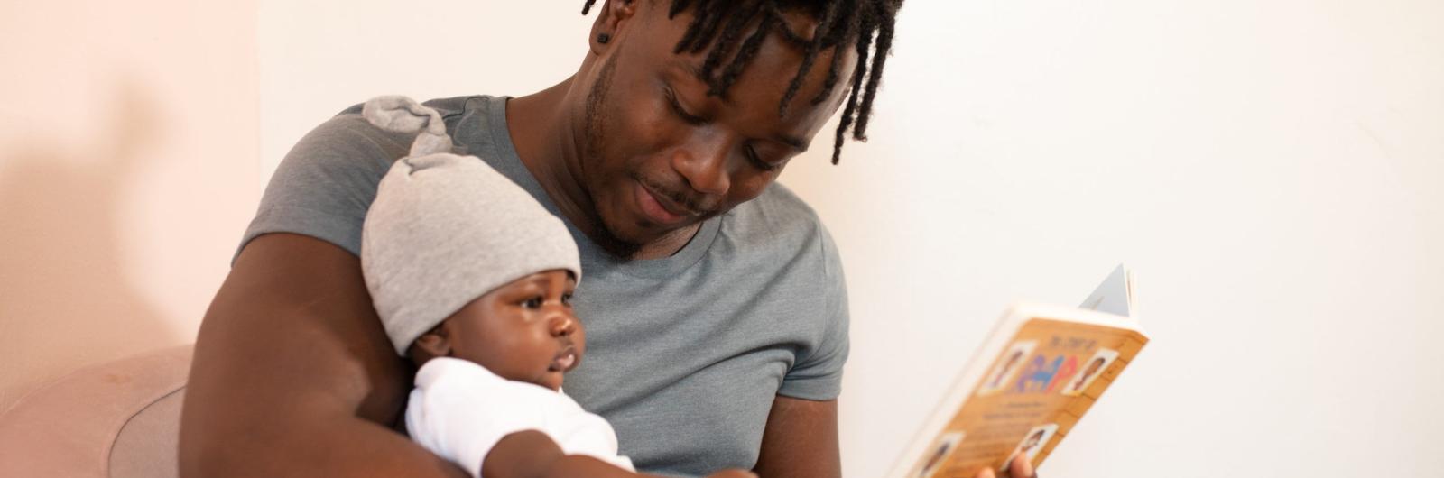 Black man and baby reading